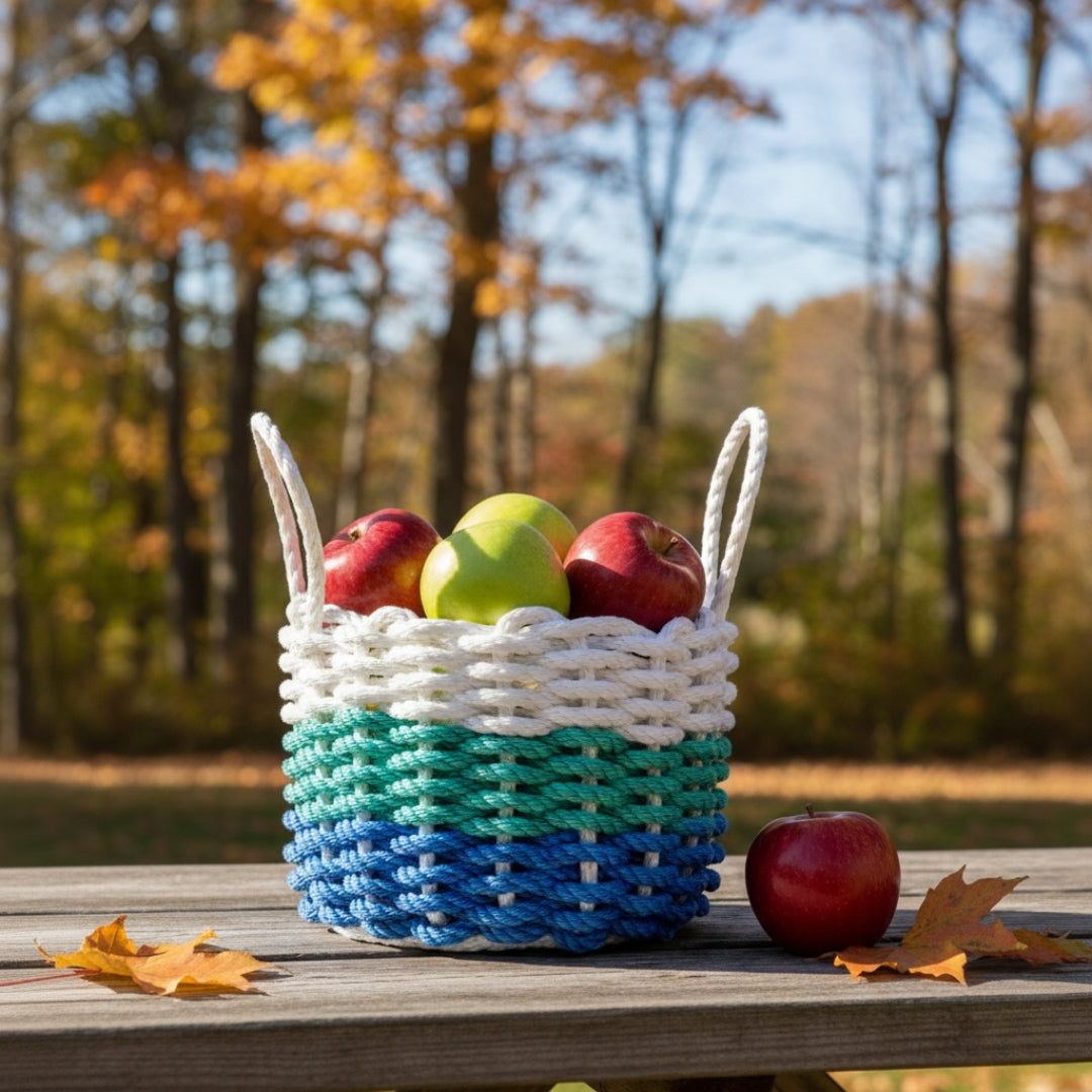 Woven basket with apples on a wooden table outdoors