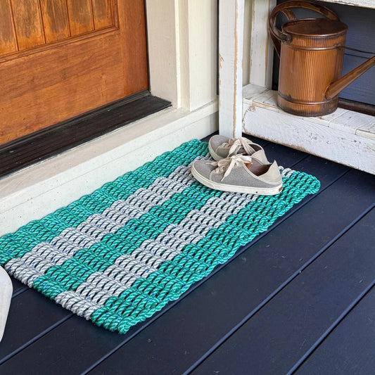 Classic Five Stripe Rope Doormat, Teal and Gray, on outdoor coastal porch with a pair of boat shoes resting on the doormat. Lollis Loops outdoor doormats are made with high quality, UV enhance marine rope so they wont fade rot or mildew