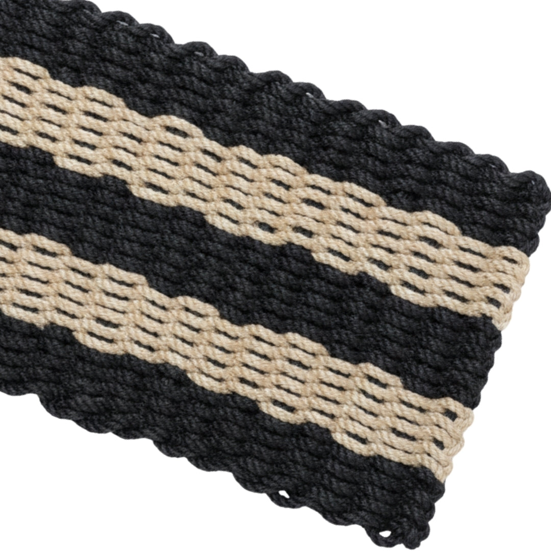 Close-up of a woven black and beige striped doormat made from reinforced, UV Resistant lobster rope. This durable welcome entryway rug is a perfect outdoor mat gift for her.