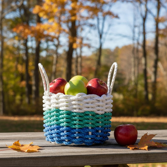Woven basket with apples on a wooden table outdoors