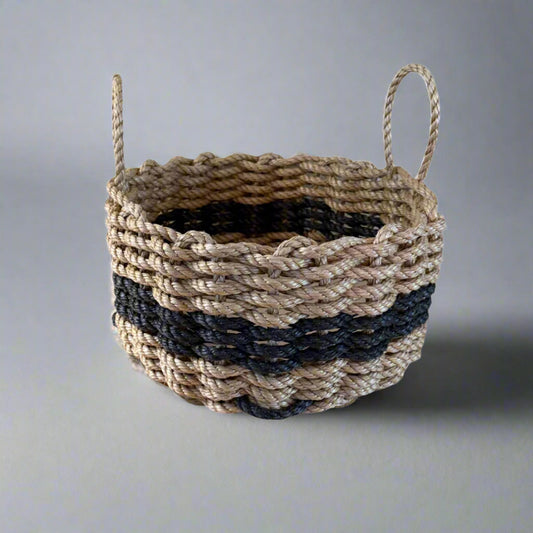 A handwoven lobster rope basket with tan and black colors, featuring handles on the sides.