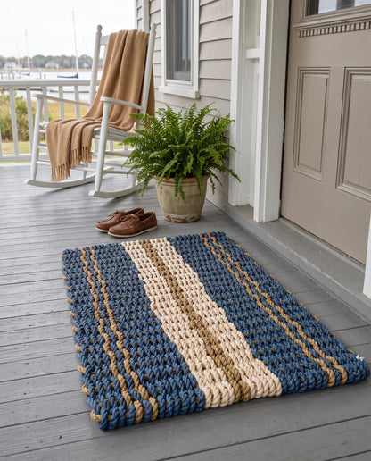 The Admiral blue, tan and sand lobster rope doormat styled at a coastal home entrance.