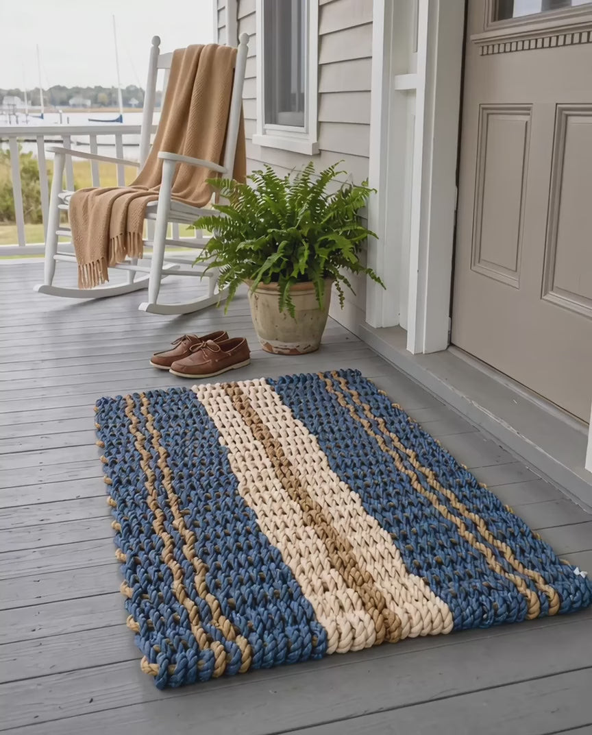 The Admiral Lobster Rope Doormat in blue, tan and sand, with paired tan stripes and a broad sand center band.